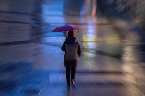 Eine Frau geht mit einem Regenschirm durch den Regen. Foto: Marijan Murat/dpa
