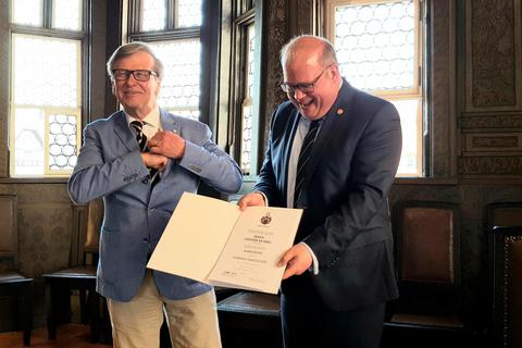 Günther Krämer wird mit der Goldenen Anstecknadel und dem Wappenteller der Stadt Alsfeld von Bürgermeister Stephan Paule geehrt. Foto: Maximilian Gerten 