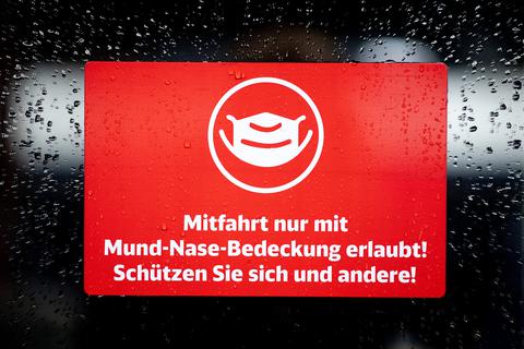 Ein Schild mit der Aufschrift "Mitfahrt nur mit Mund-Nase-Bedeckung erlaubt! Schützen Sie sich und andere!" klebt an der Zugtür eines ICE der Deutschen Bahn.