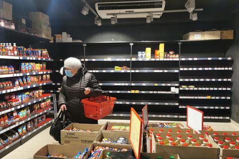 Leere Regale: In vielen Supermärkten ukrainischer Großstädte sind die Regale mittlerweile leer. Das Foto zeigt eine Frau in Lwiw. Die Fotos sind schon einige Tage alt, seitdem hat sich die Lage noch verschärft. Foto: dpa