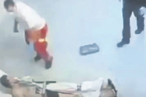 Auf dem Video ist zu sehen, wie ein Sanitäter zum Schlag gegen den Mann ausholt. Polizisten sehen zu. Screenshot: VRM/bild.de