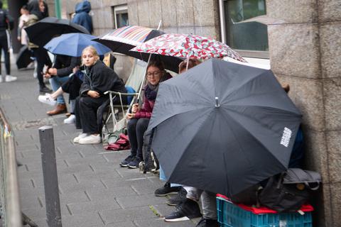 Journalisten und Prozessbesucher warten vor dem Gerichtsgebäude mit Regenschirmen und Campingstühlen auf Einlass. Foto: dpa