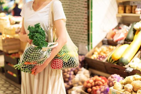 Nachhaltig Einkaufen; Frau mit Baumwoll-Shopper und wiederverwendbaren Netz-Einkaufstaschen mit Gemüse, Produkten. Umweltfreundlicher Mesh-Shopper. Zero Waste, plastikfreies Konzept